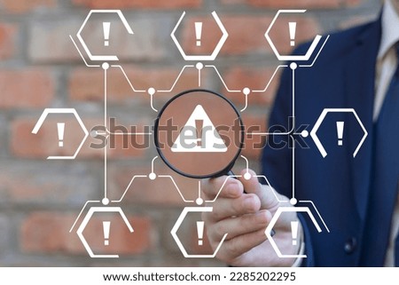 Businessman holding magnifying glass and working on virtual touchscreen of future sees icon: attention sign. Notification error and maintenance business technology concept.
