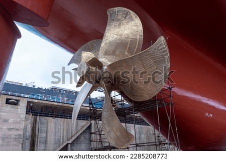 View on the container ship propeller. Ship is inside a dry dock for routine maintenance and painting. Royalty-Free Stock Photo #2285208773