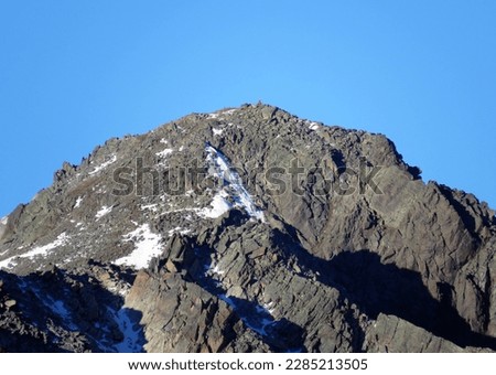 First snow on the rocky mountain peak Piz Champatsch (2946 m) in the Swiss Alps and above the mountain road pass Fluela (Flüelapass), Zernez - Canton of Grisons, Switzerland (Schweiz)