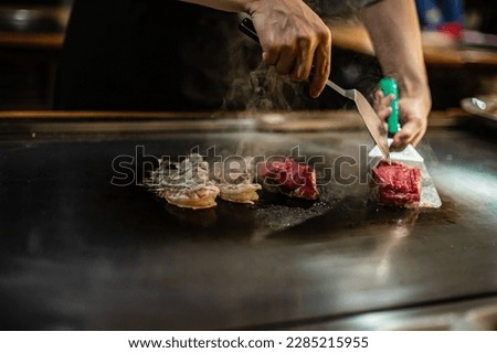 Teppanyaki, Japanese Cooking teppan show at a traditional Japanese restaurant. hands of the cook. Japanese cook prepares meat, fish, rice, vegetables on the hot table