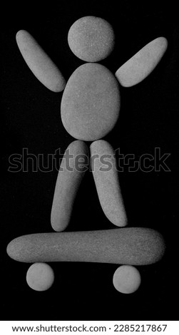 skater man on balance board.  human figure made from pebble stones. isolated on black background. hands up. skateboard. 