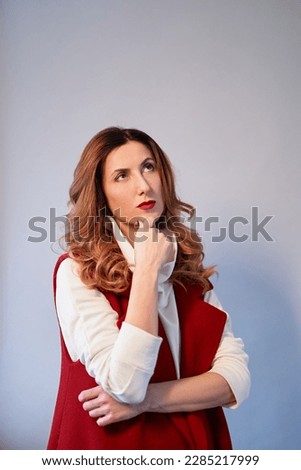 Thinking or dreaming concept. Portrait of a gorgeous caucasian brunette with wavy hair and brown eyes in elegant maroon suit with crossed arms, smiling. Copy space. High quality vertical photo