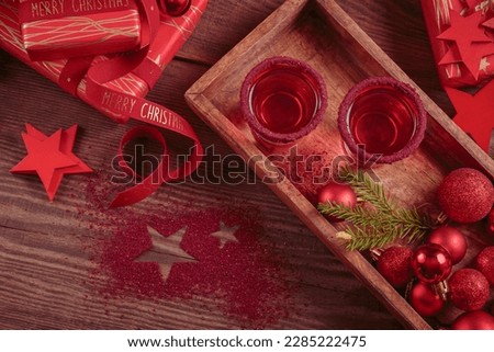 Two glasses of red liqueur on wooden background. Winter holidays, Christmas or new year party celebration concept
