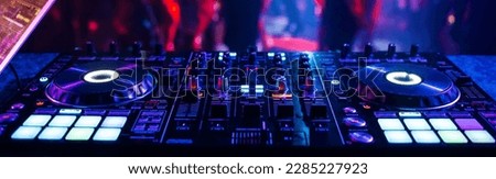 music controller DJ mixer in a nightclub at a party against the background of blurred silhouettes of dancing people Royalty-Free Stock Photo #2285227923