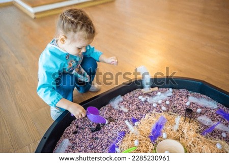 Little girl playing with sensory colorful rice. Sensory development and experiences, themed activities with children, fine motor skills development. High quality photo