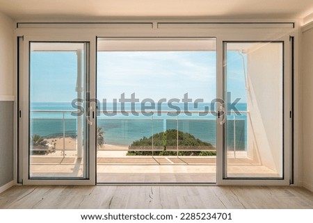 Picturesque view from a guest house through panoramic window with terrace to the sea on a sunny warm summer day with blue skies in a luxury resort. Concept of a room in a five-star hotel Royalty-Free Stock Photo #2285234701