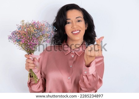 beautiful woman wearing pink shirt over white background smiling in love doing heart symbol shape with hands. Romantic concept.
