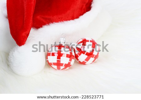 Part of Santa Claus hat with pom-pom and two red and white Christmas balls on white fur