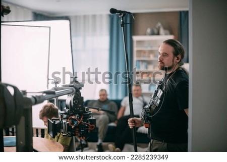 Sound engineer with a microphone on the set. A professional sound engineer at work on the filming of a movie, commercial or TV series. Filming process indoors, studio