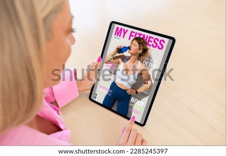 Woman reading digital edition of fitness magazine on tablet computer