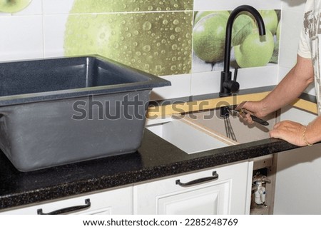 Installation of plumbing fixtures and sinks in the kitchen. The man is fixing the faucet. Royalty-Free Stock Photo #2285248769
