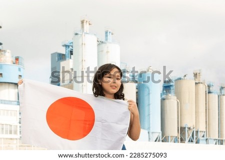 Cheerful asian female worker with japanese flag standing in front of factory