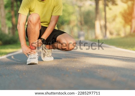 Young adult male with his muscle pain during running. runner man having leg ache due to Ankle Sprains or Achilles Tendonitis. Sports injuries and medical concept Royalty-Free Stock Photo #2285297711