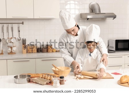 Father is teaching his son to knead dough together. Father and his son preparing pizza in kitchen. Happy family concept.
