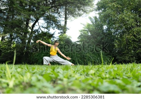 Woman practicing tai chi chuan outdoors. Practicing Tai Chi can help improve the body's flexibility, strength and balance, as well as reduce stress and anxiety. Royalty-Free Stock Photo #2285306381
