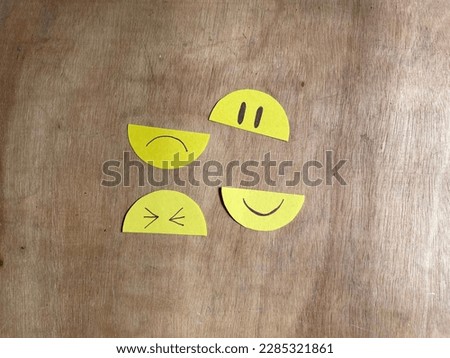 Paper Emoji face separated between eyes and mouth on wooden background. Smile and sad emoji