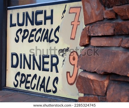 Painted window sign for lunch and dinner specials with prices at a restaurant