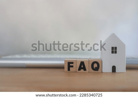 FAQ customer management analysis service for home concept, help desk and call center operator. Wooden blocks with the word FAQ place with white home and key board on the table
