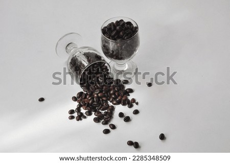 Roasted coffee beans placed in a glass cup. The object is photographed from the top angle 