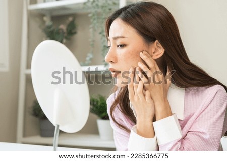 Dermatology, expression face worry asian young woman looking mirror hand touch facial at dark spot of melasma, freckles from pigment melanin, allergy sun. Beauty care, skin problem treatment, skincare Royalty-Free Stock Photo #2285366775