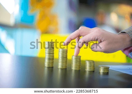 Business woman touching the third pile of coins from the right on black table, Finance and management, Concept of saving money for the future.