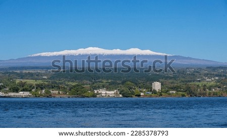 Picture of Hilo, Hawaii on a sunny day with snow-capped Mauna Kea in the backgroundl 