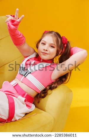 a beautiful teenage girl in a pink stage costume in the chair on a yellow background. the concept of children's pop music. poster or cover for a music album or song.