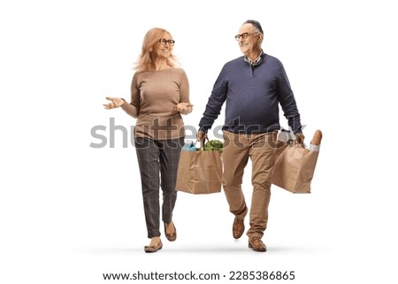 Full length portrait of a mature man walking, carrying grocery bags and having a conversation with a woman isolated on white background