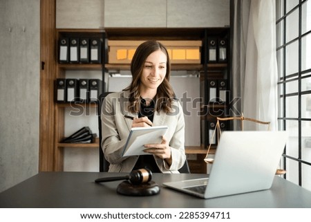 Asian lawyer woman working with a laptop and tablet in a law office. Legal and legal service concept. Looking at camera
