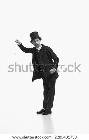 Day scheduled in minutes. Black and white portrait of retro gentleman wearing vintage suit and holding pocket watch. Concept of english culture, comparison eras, vintage, retro Royalty-Free Stock Photo #2285401733