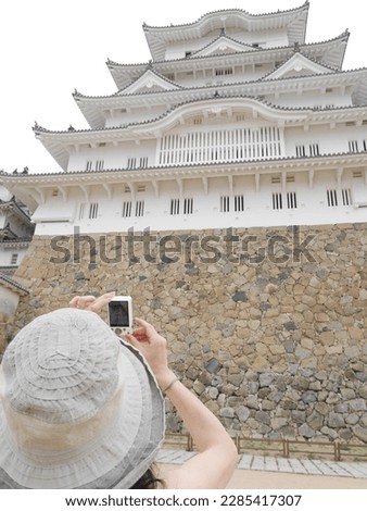 A woman taking pictures of Himeji Castle for sightseeing