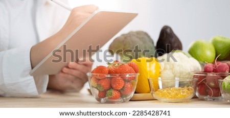 Panoramic of hand professional nutrition healthful surrounded by a variety of fresh fruits and vegetables working on digital tablet. Concept of right nutrition, diet and healthcare. Royalty-Free Stock Photo #2285428741