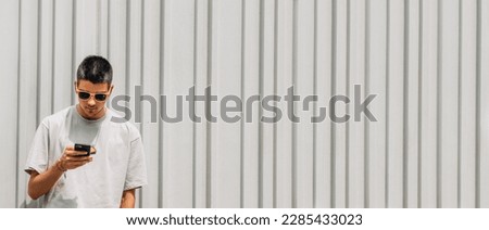 boy with mobile phone and sunglasses on the wall on the street in summer