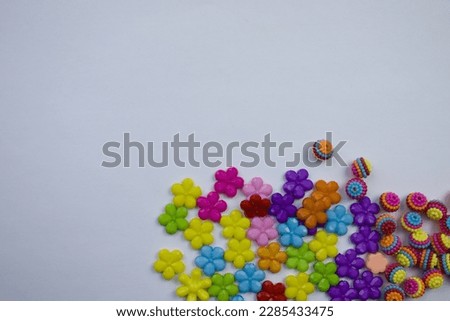 Differences, similarities.  Colorful flowers balls, photographed from above, placed on the edge of a white background.  Differences, similarities.