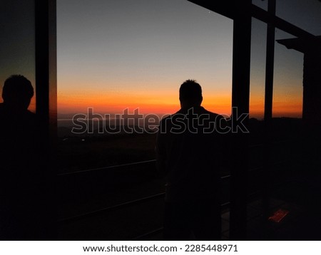 silhouette of man taking photo of sunset with camera