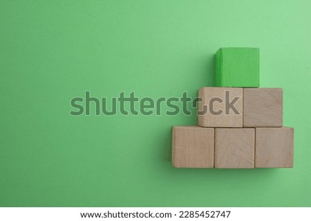 Green wooden cubes for put text,logo or infographic stacking in pyramid shaped in right corner with copyspace over Green  background use for lat lay top view mock-up item,business and design concept.