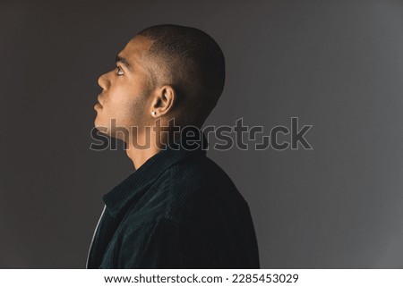 Side profile shot of young African American man with buzz cut on a grey dark studio background . High quality photo Royalty-Free Stock Photo #2285453029