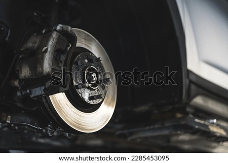 Disc brake of the vehicle for repair, in process of new tire replacement. Car brake repairing in garage. High quality photo Royalty-Free Stock Photo #2285453095