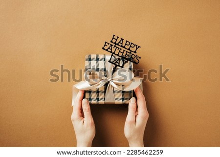 Happy Fathers Day concept. Female hands holding vintage gift box with sign Happy Father's Day over brown background.