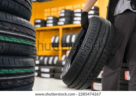 A tire changer checks new tires in stock to take them to a service center or auto repair shop. Tire warehouse for the automobile industry