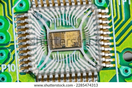 Closeup of electronic integrated circuit die with photodiode array and gold wires on green PCB. Micro chip inside optical computer mouse image sensor in plastic package with round hole and metal pins. Royalty-Free Stock Photo #2285474313