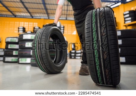 Asian male tire changer Check new tires in stock for replacement at a service center or auto repair shop. Tire warehouse for the automobile industry