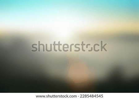 Natural fog and mountains sunlight background blurring, misty waves warm colors and bright sun light. Christmas background sky sunny color orange light patterns, abstract flare evening on clouds blur.