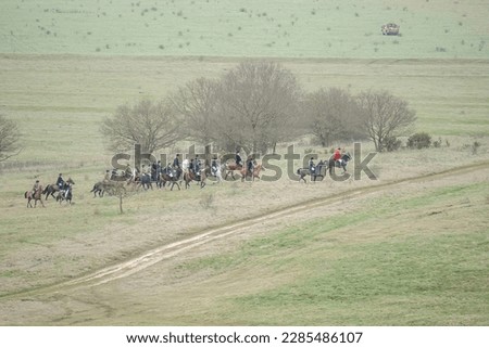 horse riders engage in the hunt for a fox (Vulpes vulpes) in winter countryside