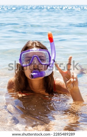 girl is engaged in scuba diving in a clean clear sea. young girl dressed in glasses and a tube for swimming.
