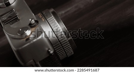 Close up of the Old vintage camera lens  on a rustic wooden table against with a low light background - black and white 
