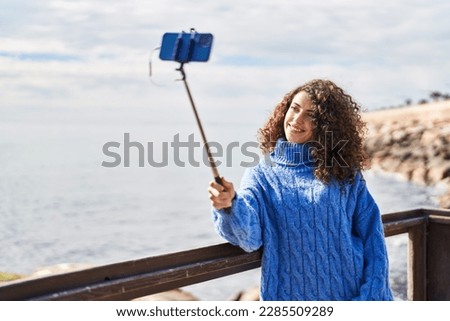 Young hispanic woman smiling confident make selfie by smartphone at seaside