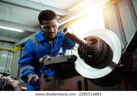 african american engineer. Technicians, workers, engineers working with metal lathes in industrial plants. A mechanic works on a metal lathe in a factory. CNC Laser cutting industrial technology.