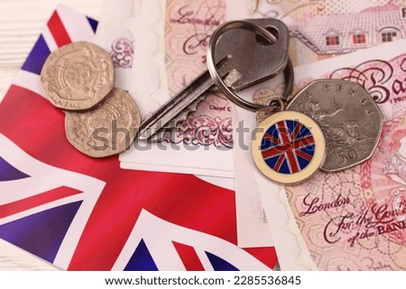 UK money bills and key for house close up. Big amount of United Kingdom pounds and silver key on table. Business and real estate concept for England