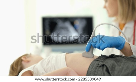 Doctor gastroenterologist making ultrasound examination of liver and pancreas to child in clinic closeup Royalty-Free Stock Photo #2285539049